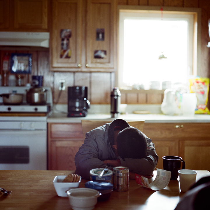 NEWTOK, ALASKA - 2008: Boy sleeping at dining room table at Peter Johns home.