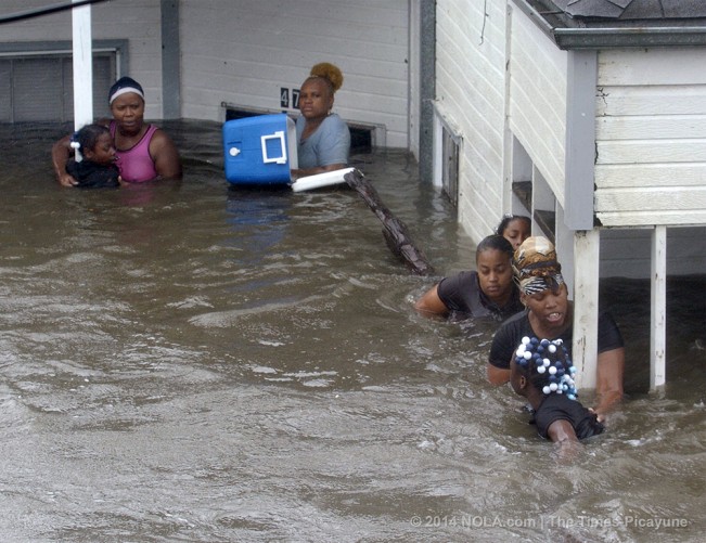 STAFF PHOTO BY TED JACKSON A family of women and children cling to posts on their front porch as rising flood waters force them to evacuate their home on St. Claude Ave in the Lower 9th Ward. They had tried to get into their attic space to no avail. Flood waters raging down St. Claude prevented rescuers from reaching them during the storm. They were planning to swim to safety using the log in the lower right of photo, as spectators pleaded with them to stay where they were until help could arrive. They said they had been clinging to the posts since 8 am. It was now after noon.  Hurricane Katrina. August 29, 2005