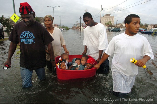 STAFF PHOTO BY JOHN MCCUSKER The hurricane has passed and the flooding has begun Monday afternoon as three men - John Rainey, John Rainey, Jr. and Courtney Davis -  help Terry Fox tug a tub full of children toward an overpass on South Broad Street, August 29, 2005