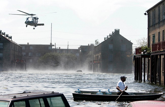 STAFF PHOTO BY ALEX BRANDON A blackhawk helicopter rescues people in the B.W. Cooper project as a man goes back to his apartment following Hurricane Katrina in New Orleans on Wednesday, Sept. 7, 2005.