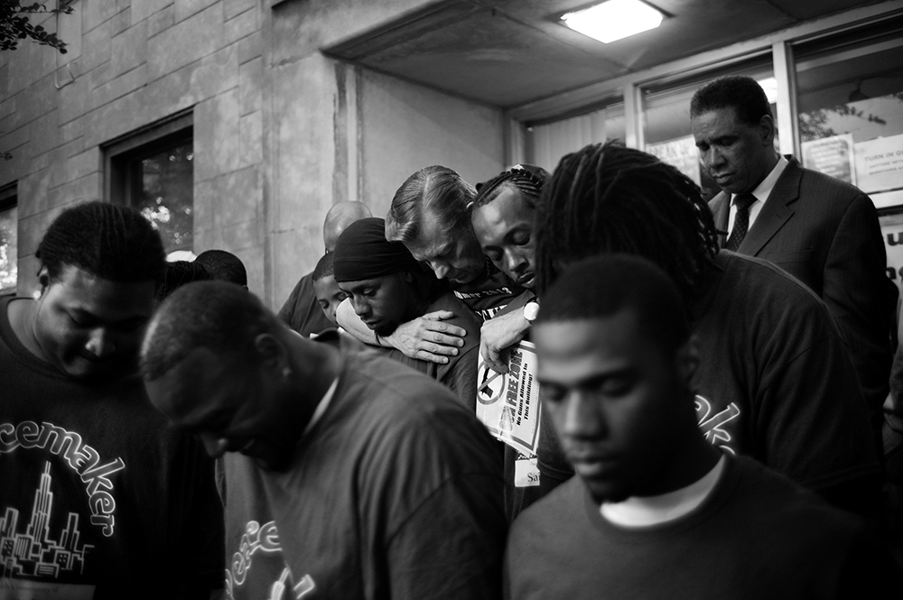 Rev. Michael Pfleger of St. Sabina Church embraces young men who are working to break the cycle of violence during a prayer service. Auburn Gresham, Chicago, 2013