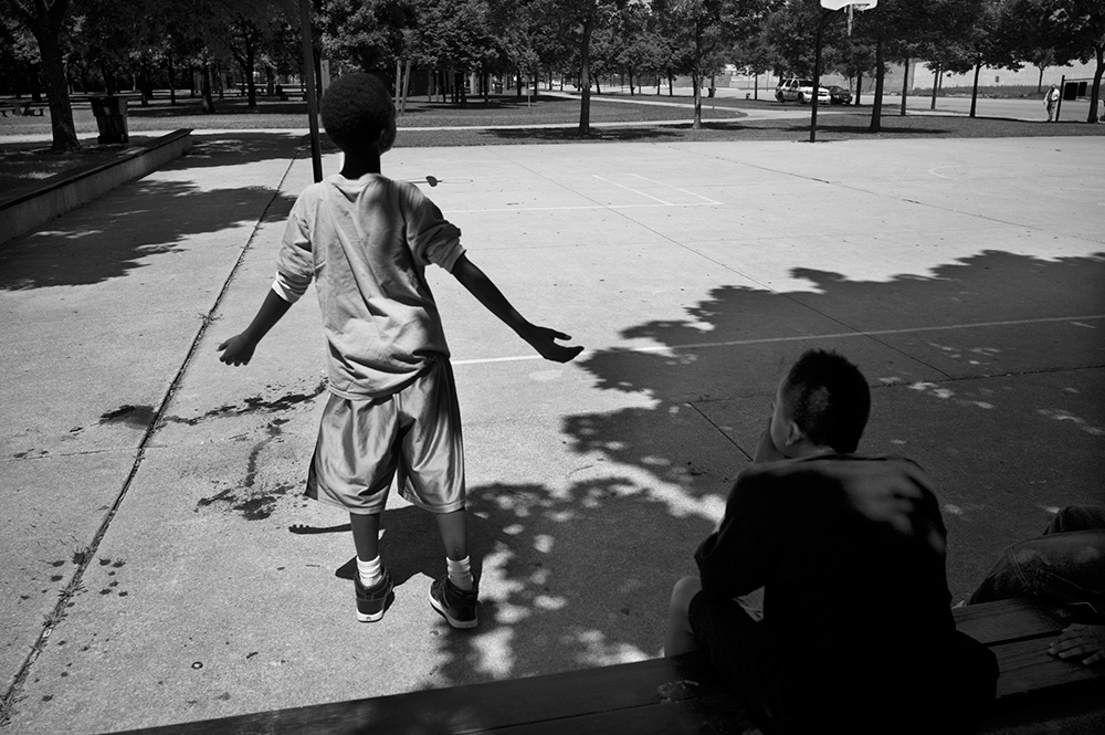 Darius Brown was playing basketball with his friends at Metcalfe Park when a white car drove by and sprayed the crowd of young people with bullets. The next day, the playground was stained with blood. Protests and a cry for peace followed. Bronzeville, Chicago, 2011