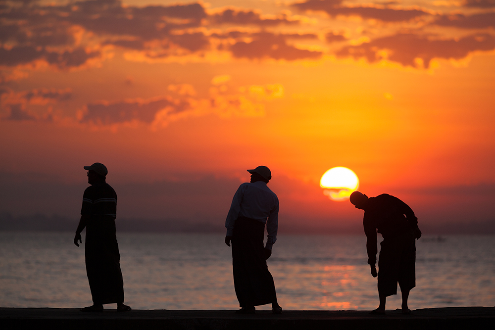 Three men doing morning exercise in silhouette as the sunrises