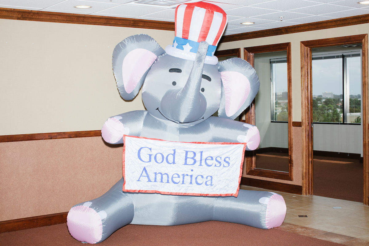 An inflatable elephant holding a sign reading "God Bless America" sits in a hallway near the Palm Beach Republican Club and West Palm Beach Victory Headquarters office in West Palm Beach, Florida. The office serves as a place for volunteers to gather and organize for various Republican campaigns, including Donald Trump's general election campaign.