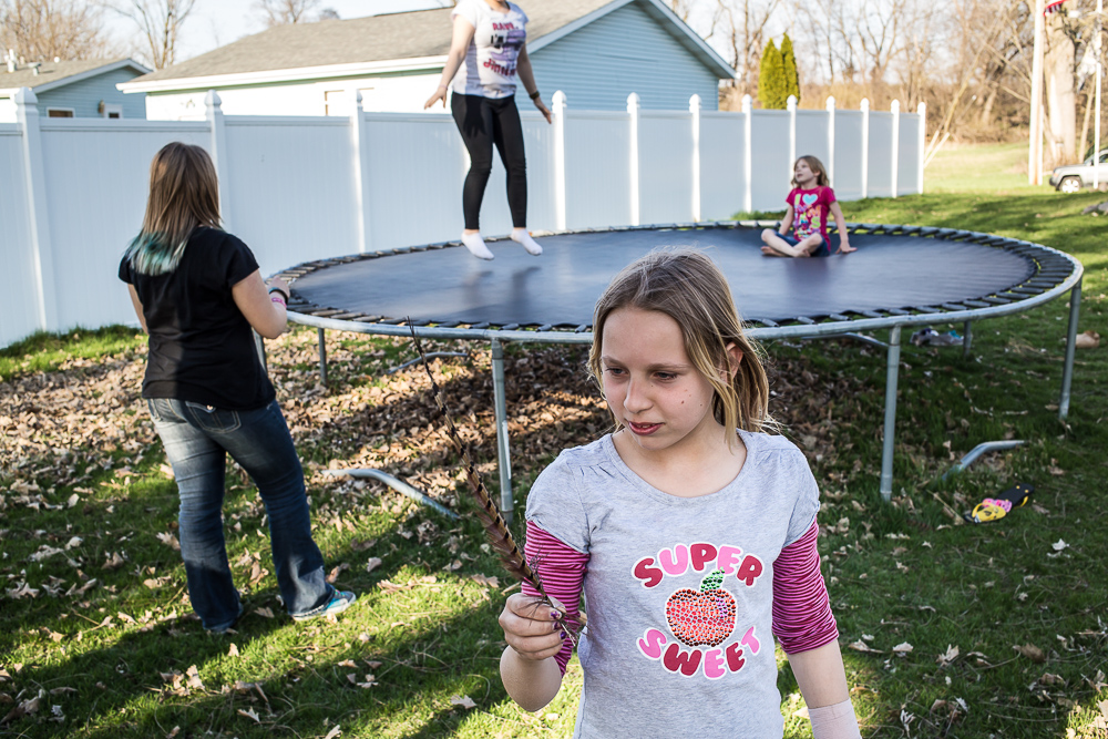Girls play with a found feather and trampoline in their back yard on Sunday, April 28, 2013 in Webster City, IA.
