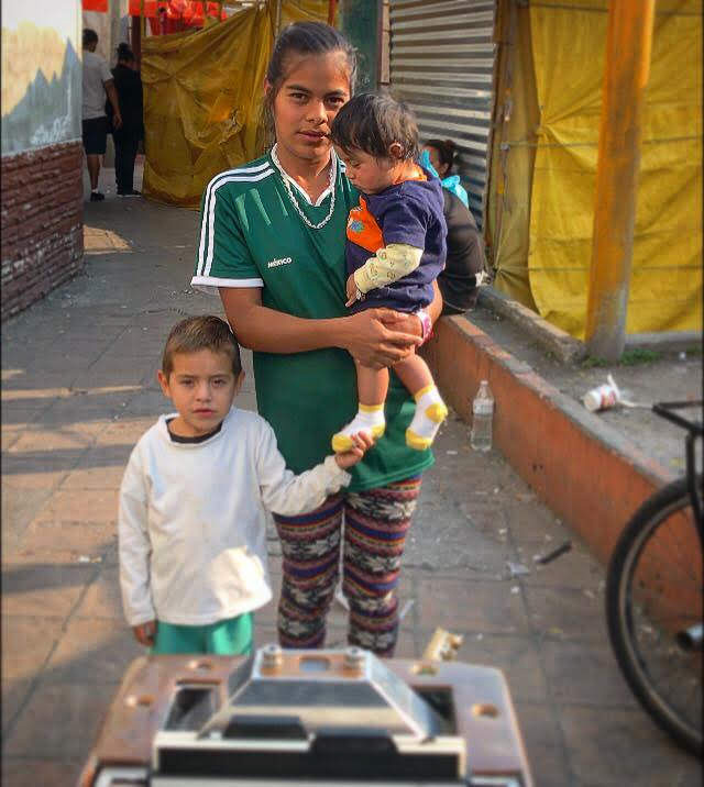 © Wayne Martin Belger, "Us & Them" Migrant Caravan photo shoot of woman with two children at a migrant housing facility set up by Father Alejandro Solalinda in Mexico City.