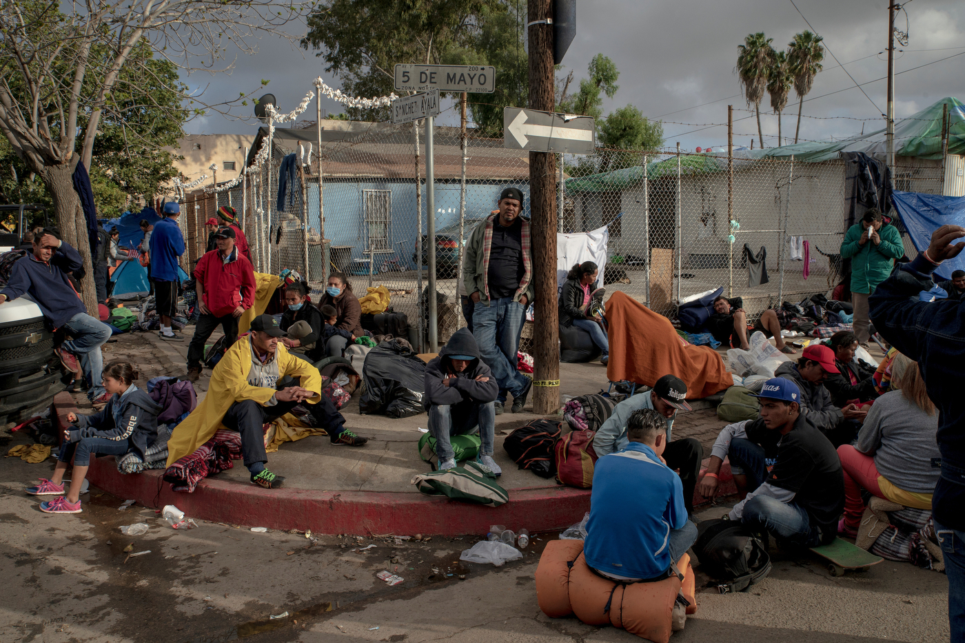 A group of migrants wait before being transferred to a different temporary shelter in Tijuana, Mexico on November 30, 2018. Mexican officials required all the migrants to leave the Benito Juarez encampment due to safety and hygienic concerns and move instead to the outskirts of Tijuana to the El Barretal complex. Photo by Kitra Cahana / MAPS
