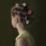 young girl with hair in thread spool rollers - green background