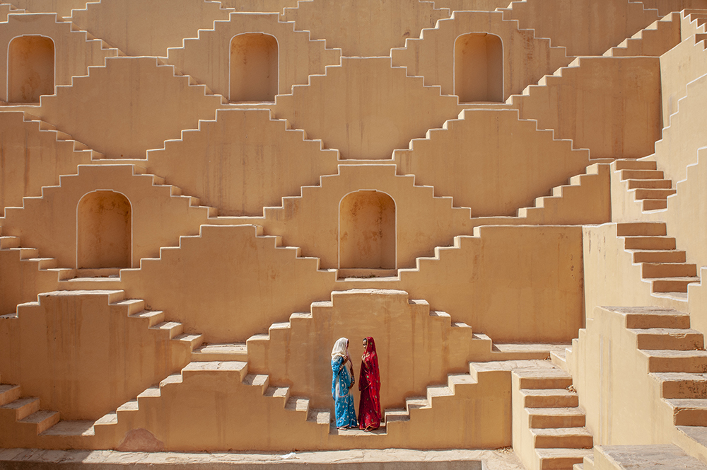 Jasmin (wearing red) and Manisha Singh (white and blue sari) pose at the Baoli at Amer, a water well in the city of Japiur in India's Rajasthan Thar desert. (Photo by Ami Vitale)
