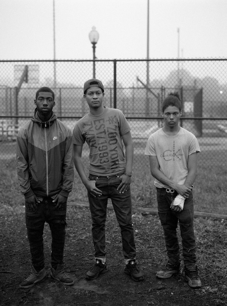 Three friends stands in front of the basketball court