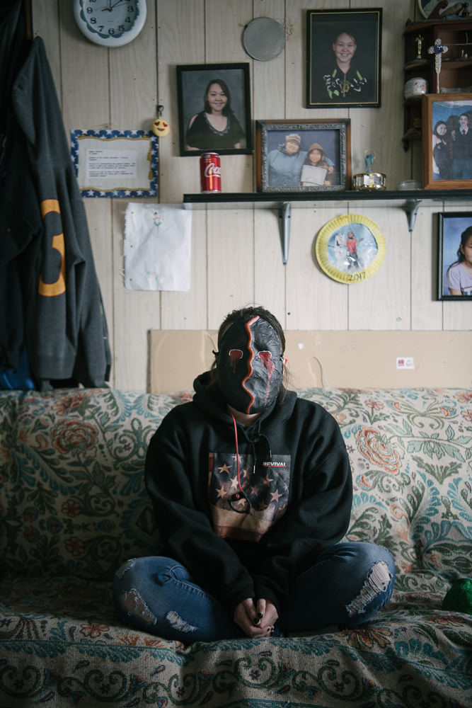 LA reflects on family and loss at home in her mask of grief. Though her family has more than most, she is not insulated from the near-constant stream of deaths in the community, from cancer to suicide. April 12, 2018, Gambell, AK.