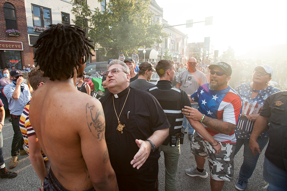 A clergyman attempts to keep the peace after a Black Lives Matter supporter was assaulted by attendees at the Red, White and Blue rally in front of the Monroe County Courthouse on Saturday August 22, 2020. (Zachary Kaufman / for The Bloomingtonian)