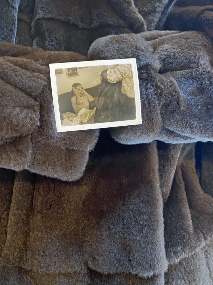 Color photograph of a mink coat with a photo of a woman surpised by a man with a mink coat on top of it in sepia.
