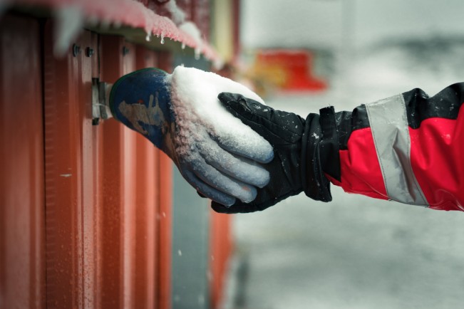 An expeditionary shakes hands with a frozen glove hanging on Module 7 under construction at the Pedro Vicente Maldonado Antarctic Station in Shetland peninsula.