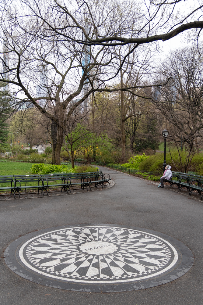 A woman sits in Central Park by the Imagine circle.