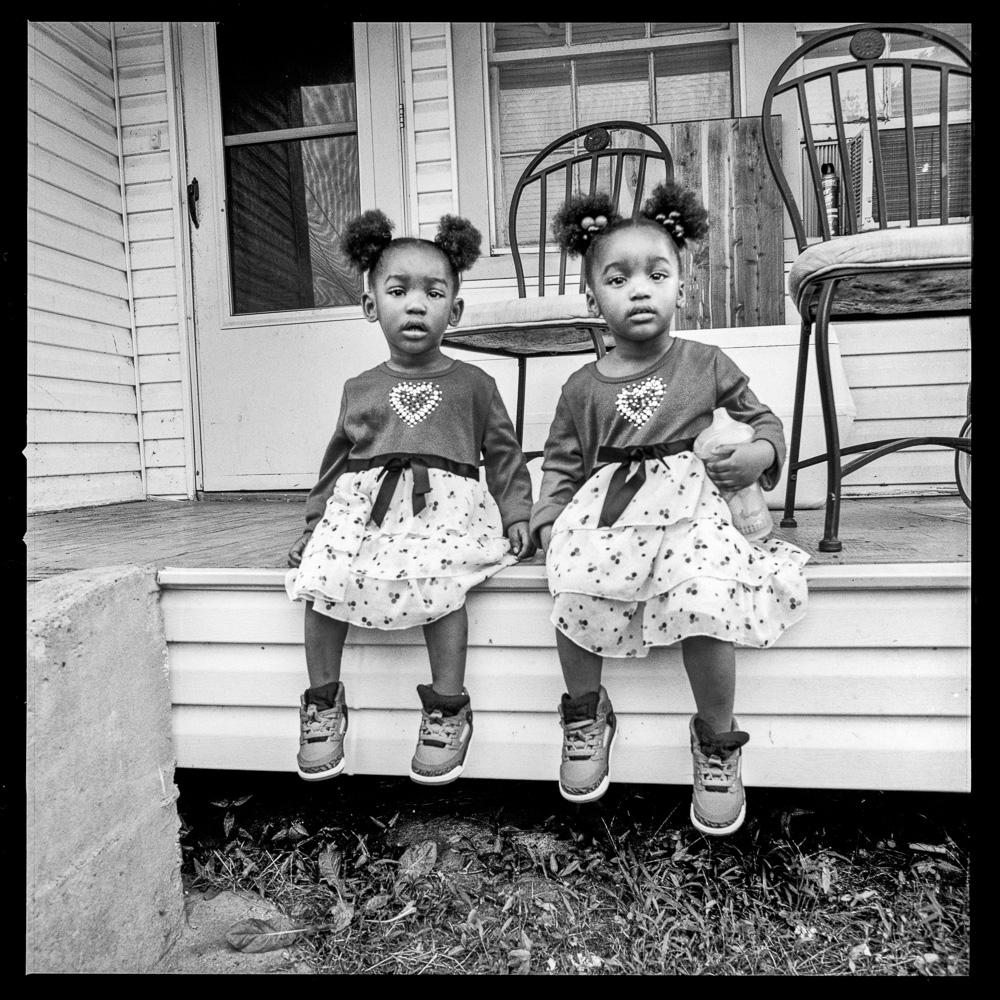 Katie and Kyley, 2 year old twins pose on their front porch.  They are a little unsettled having this white woman with a big old camera taking their photos.  But their uncle Samuel Sullivan who is taking care of them says it's ok.  Their home is next to one of entrances to Watkins Cemetery where many victims from the horrible fire in the Rhythm Club Jukejoint were buried in 1940.