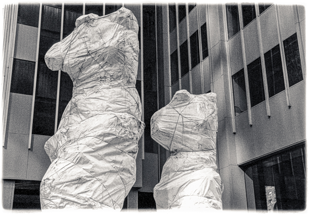 July 5, 2019 - Wrapped sculptures at the corner of 52nd Street and the Avenue of the Americas (6th Ave) in NYC. The two sculptures by artist Jim Dine are bronze renderings of "Venus de Milo" statues and with a 3rd sculpture on 53rd street are collectively titled "Looking Toward the Avenue". I happened to be in NYC in the fall of 1989 when the sculptures were being delivered and were still wrapped. Only recently did I happen to walk by and realize the wrapped sculptures weren't the final art. So, now I feel better about "owning it".