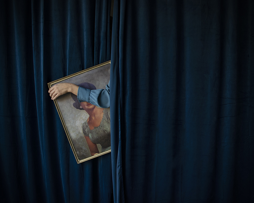 Woman in blue curtain holding picture