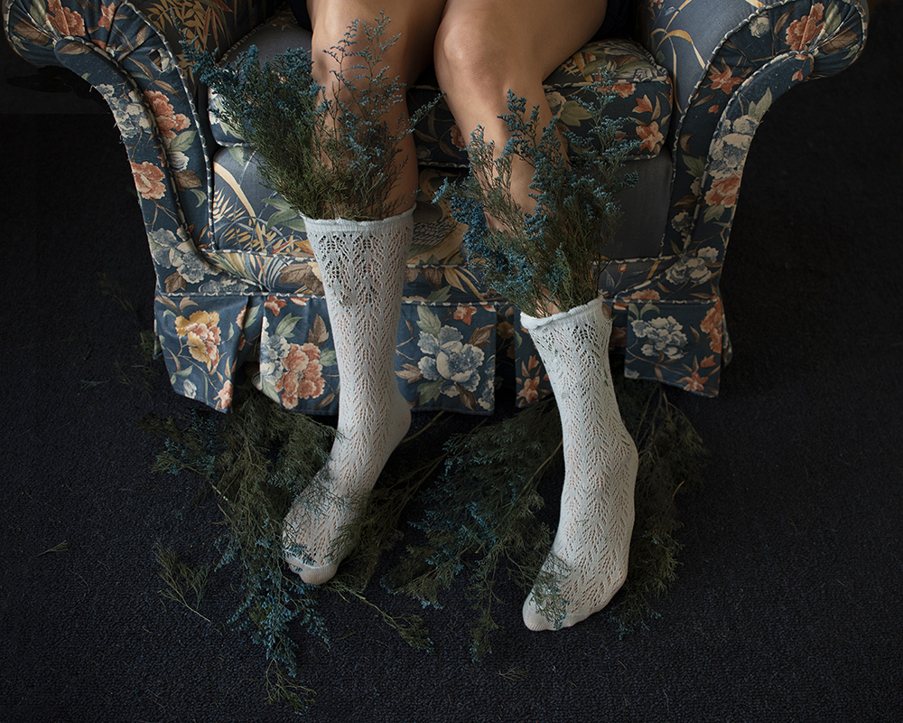 woman on blue floral chair with blue flowers tucked in her socks