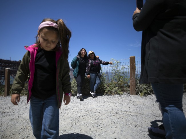 D- Aubrey Smith, 5, walks away as her relatives Karla and Vicky Beña pose for a photo by the Golden Gate Bridge on Saturday, May 20, 2022 in San Francisco, California.