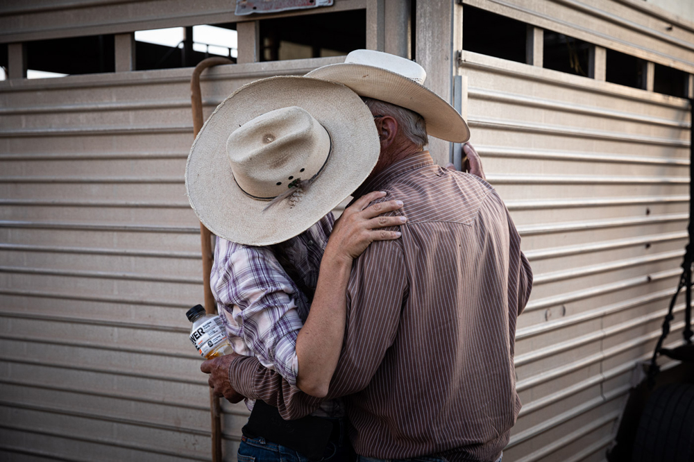 Amanita and Tom Berto pause for a kiss next to their goat trailer. They were hired to bring their herd to La Cienega, New Mexico to reduce the risk of fire by clearing overgrown areas.