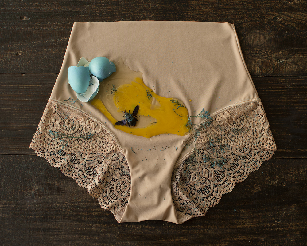 Underwear with cracked blue egg and blue carpenter egg on top of.