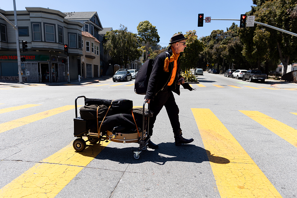 A: Brian Belknap crosses Bosworth Street after taking the subway home from a long morning of playing music at Ferry Plaza. Although he enjoys the streets of San Francisco, he dreams of returning to his home in New Orleans to play music on Bourbon Street.
