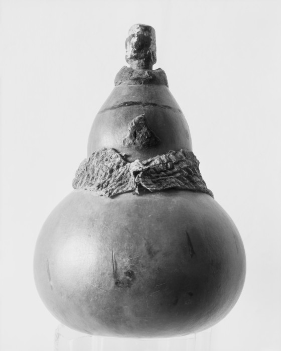 A gourd, with a snake skin collar and a dip stick stopper, used for medicine that is applied to the wounds  of FGC.