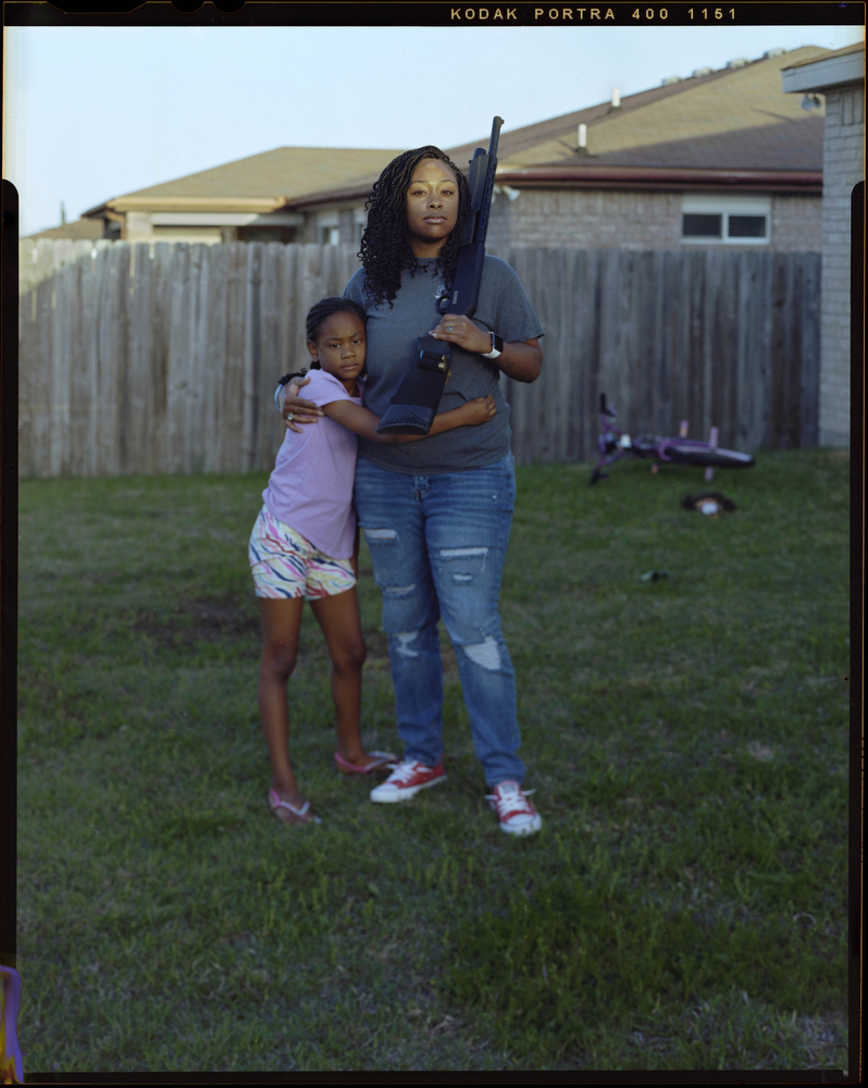 Damillah Lane, 26, is embraced by her daughtyer Skylar Lane, 8, as she holds her firearm outside of her home on Saturday, April 10, 2021 in Killeen, Tx. “Whenever my husband leaves I feel a need to protect my family,” Damillah said.