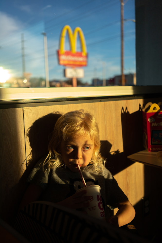 Lily, Felicia and DavidÕs daughter, 8, sips on a soda in a McDonalds in Albuquerque, NM, 2020.