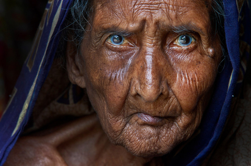 SomeJarn, over 100 years old, has lived in the Chars of north-western Bangladesh her whole life. Chars are shifting sandbar islands within the Jamuna-Brahmaputra river system. These islands, out of which many are covering less than a square mile, appear and vanish with the floods and the flow of sediments from upriver forcing local inhabitants to move frequently, each time their land disappears under the water. 