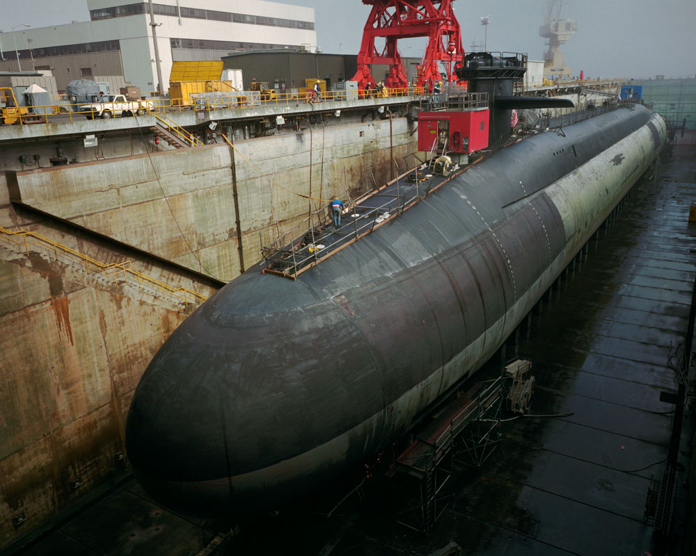 Ohio class Trident submarine, USS Alaska in dry dock for refit, Bangor Naval Submarine Base, Washington. The Trident weighs 18,750 tons (submerged), is 560 feet long, and carries a crew of 155 men. Each submarine carries up to 24 multiple-warhead missiles.
