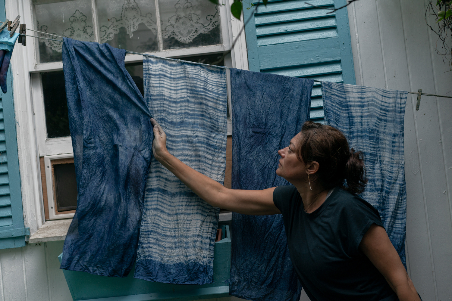 Caroline Harper, an artist who recently moved to Charleston, straightens out some of her scarves dyed with indigo. She and her husband are growing indigo on nearby Edisto Island and processing it into dye. They have received a USDA grant to scale indigo production.