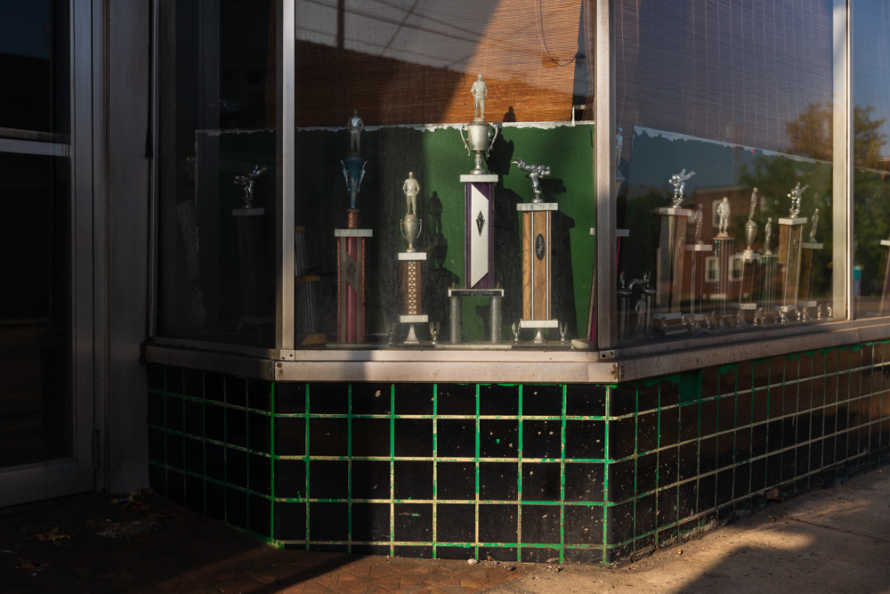 Trophies in the window of a closed martial arts studio in Clairton, Pennsylvania. In many of the small towns I visit, a familiar sight to see are empty storefronts with old trophies or memorabilia in the windows. More often than not the trophies are for the accomplishments of local youth sports, or bowling leagues. To me at least, these trophies are left and displayed as a sense of local pride for those people who still live in these towns, and to remind those just passing through that they are not to be so easily dismissed or forgotten.