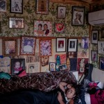 Ruiha Te Tana (12) relaxes at her grandfather's home in Ruatoki, New Zealand. Built by an ancestor in 1916, the homestead serves as a living archive of Tūhoe history. The wall of photographs visually represents Te Tana's whakapapa, or genealogy, a cornerstone of Maori culture. Whakapapa connects individuals to their ancestors, land, and tribal identity, providing a sense of belonging and continuity.